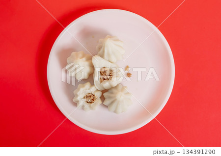 Steamed sweet modak rice dumplings on a white plate against a bright red background 134391290