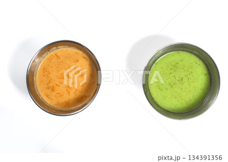Spicy red chutney and green chutney served in stainless steel bowls on white background. 134391356