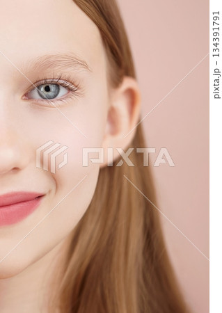 Half face. Portrait of a funny smiling blonde young girl posing in studio pink background. Advertising beauty Skincare products for teens or kids. Haircare. Self care Generation Alpha. Copy space Half face. Portrait of a funny smiling blonde young girl posing in studio pink background. Advertising beauty Skincare products for teens or kids. Haircare. Self care Generation Alpha. Copy space 134391791