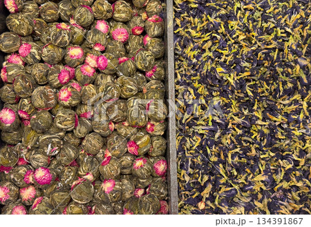Blooming green tea balls with embedded flowers arranged beside loose petals in Istanbul bazaar. Artisanal tea craftsmanship, visual ritual, and botanical infusion culture highlighted through form and Blooming green tea balls with embedded flowers arranged beside loose petals in Istanbul bazaar. Artisanal tea craftsmanship, visual ritual, and botanical infusion culture highlighted through form and 134391867
