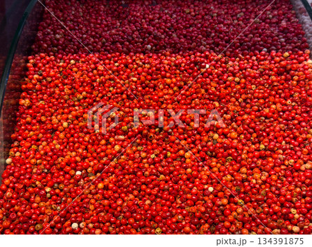 Red peppercorns densely covering a spice tray in a vivid textured layer in Istanbul bazaar. Culinary seasoning, aromatic intensity, and global cooking traditions highlighted through color and 134391875