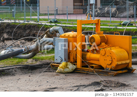 Industrial dewatering pump with hoses operating at construction site for groundwater removal 134392157