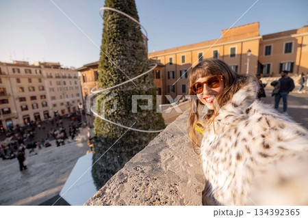 Smiling woman taking festive selfie with city view in Rome during holiday season 134392365