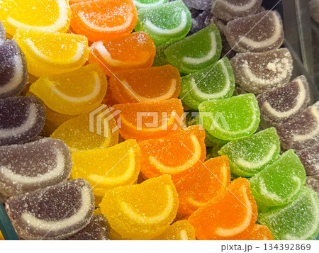 Colorful fruit jelly slices covered with sugar crystals arranged in a market container in Istanbul bazaar. Playfulness, nostalgia, sweetness, and visual joy through classic candy assortment and vivid Colorful fruit jelly slices covered with sugar crystals arranged in a market container in Istanbul bazaar. Playfulness, nostalgia, sweetness, and visual joy through classic candy assortment and vivid 134392869