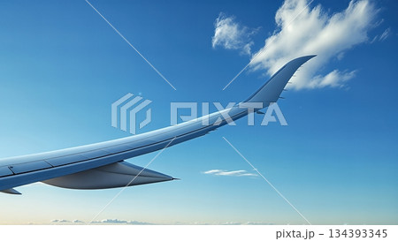 View of an Airplane Wing Against a Clear Blue Sky During Daytime Travel Over Distant Clouds View of an Airplane Wing Against a Clear Blue Sky During Daytime Travel Over Distant Clouds 134393345