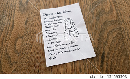 Spanish prayer text with illustrated woman in prayer on wood surface 134393508
