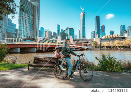 cyclist by river, urban commuter in helmet and hoodie enjoying tranquil morning by river 134393538