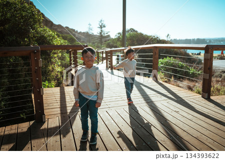 Children are joyfully playing together on a beautiful wooden deck by the beach, enjoying their time 134393622