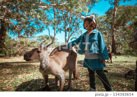 Child Interacting with a Kangaroo in a Serene Natural Setting 134393654