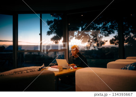 Young Professional Working Late into the Evening with a Stunning Sunset View in Sight 134393667