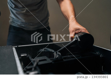 Close-up of computer technician cleaning desktop computer interior with portable air blower, maintaining hardware performance and preventing potential system overheating in professional workshop. Close-up of computer technician cleaning desktop computer interior with portable air blower, maintaining hardware performance and preventing potential system overheating in professional workshop. 134393801