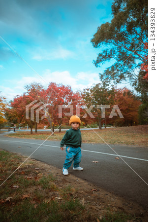 child wearing yellow beanie standing pensively along colorful autumn street scene child wearing yellow beanie standing pensively along colorful autumn street scene 134393829
