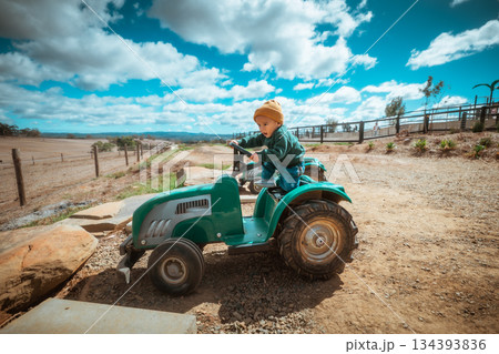 A Child Enjoys Riding a Colorful Toy Tractor on a Beautiful Farm A Child Enjoys Riding a Colorful Toy Tractor on a Beautiful Farm 134393836