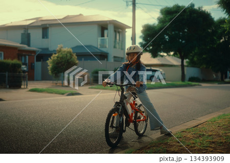 A Young Biker is Thriving While Enjoying a Beautiful and Sunny Day on Her Bicycle 134393909