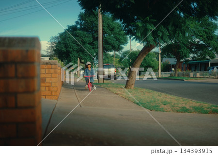 A Child Happily Riding a Bicycle on a Peaceful Suburban Street Today A Child Happily Riding a Bicycle on a Peaceful Suburban Street Today 134393915