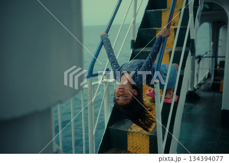 Joyful Child Playing on a Ship's Staircase under Gloomy Skies 134394077