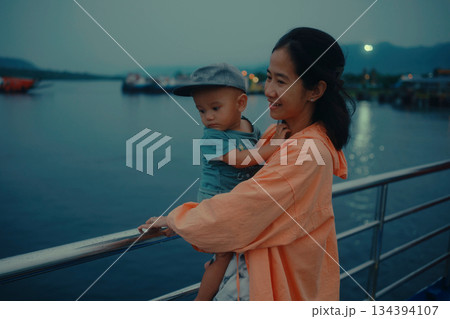 A peaceful Mother and Child by the Water at Dusk during a beautiful evening together 134394107