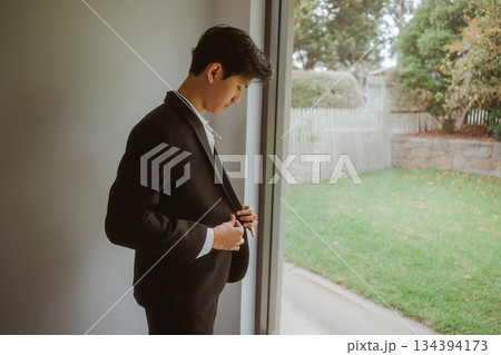 A Young Man Dressed Smartly in a Suit is Getting Ready for a Special Occasion A Young Man Dressed Smartly in a Suit is Getting Ready for a Special Occasion 134394173