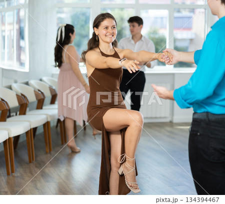Couple in evening dresses enjoys pair dance boogie-woogie, interacting with each other on floor Couple in evening dresses enjoys pair dance boogie-woogie, interacting with each other on floor 134394467