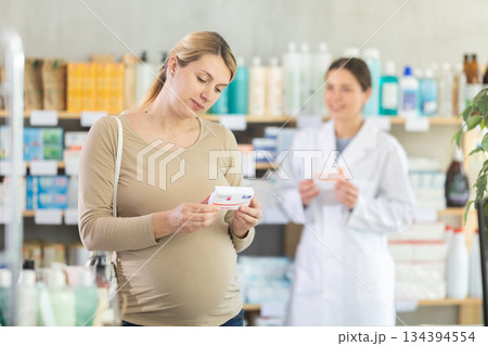Pharmacist helping pregnant woman choose prenatal vitamins 134394554