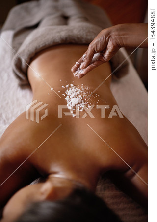Salt sprinkle, back scrub and spa specialist hands with woman customer at a hotel with massage. Exfoliate therapy, luxury and relax treatment of a female person rest for skincare and wellness Salt sprinkle, back scrub and spa specialist hands with woman customer at a hotel with massage. Exfoliate therapy, luxury and relax treatment of a female person rest for skincare and wellness 134394881