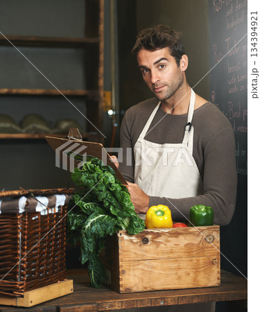Chef, checklist and portrait of man in restaurant with vegetables for vegetarian or vegan ingredients. Serious, male cook with clipboard and food from Norway for cooking in kitchen or small business. 134394921