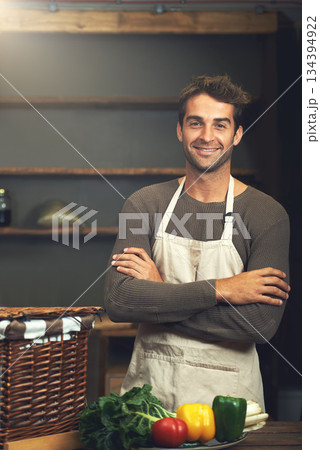 Chef, smile and portrait of man with arms crossed in rustic kitchen with vegetables for nutrition and vegan ingredients. Confidence, male cook and happy person from Norway ready to start cooking. 134394922