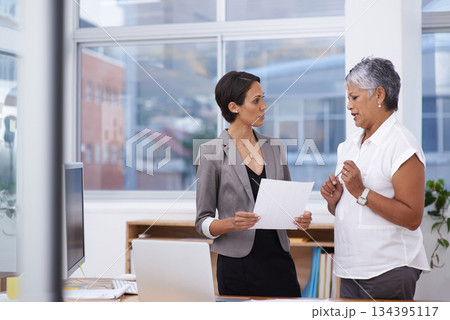 Paperwork, talking and business women or team in office for planning, brainstorming or advice. Corporate employee and manager or mentor together for discussion, collaboration or teamwork on a report 134395117