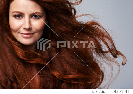 Redhead, wind and hair portrait of woman in studio for treatment, wellness and beauty on gray background. Salon, hairdresser and happy face of female model with shine, healthy and natural hairstyle 134395141
