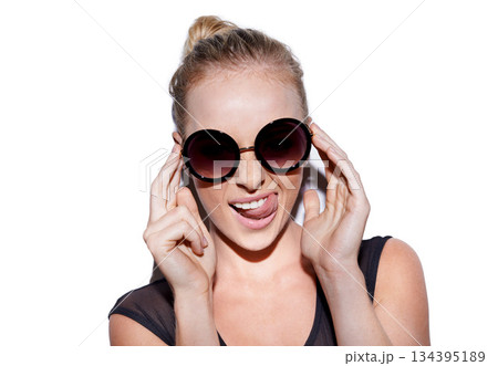 Portrait, tongue out and sunglasses or trendy woman for fashion in studio or positive and isolated on white background. Face, female model and crazy or smiling hipster or glamour and lipstick Portrait, tongue out and sunglasses or trendy woman for fashion in studio or positive and isolated on white background. Face, female model and crazy or smiling hipster or glamour and lipstick 134395189