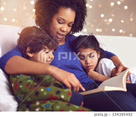 Children, mother and reading a book in a family home for story time on lounge sofa with bokeh. A woman or mom with kids together for development, learning and love with a fantasy, magic or fairytale Children, mother and reading a book in a family home for story time on lounge sofa with bokeh. A woman or mom with kids together for development, learning and love with a fantasy, magic or fairytale 134395492