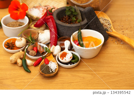 Mortar, food and spices on table for cooking gourmet meal, chili seasoning or flavor pestle. Pepper vegetables, kitchen condiments and variety of plant herbs for brunch, healthy diet or vitamins. Mortar, food and spices on table for cooking gourmet meal, chili seasoning or flavor pestle. Pepper vegetables, kitchen condiments and variety of plant herbs for brunch, healthy diet or vitamins. 134395542