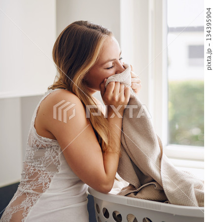 Smelling, woman and laundry with clothes in basket and happy with clean apartment towel. Female person, cleaning or fabric for self care, lifestyle and happiness in a household with fresh clothing. Smelling, woman and laundry with clothes in basket and happy with clean apartment towel. Female person, cleaning or fabric for self care, lifestyle and happiness in a household with fresh clothing. 134395904