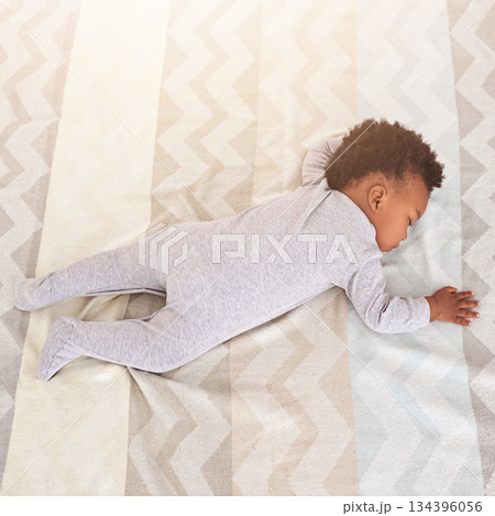 Top view, bed and baby sleeping in nursery with lens flare for rest, nap time and dreaming in home. Childcare, newborn and cute, tired and African child in bedroom sleep for comfort, relax and calm 134396056