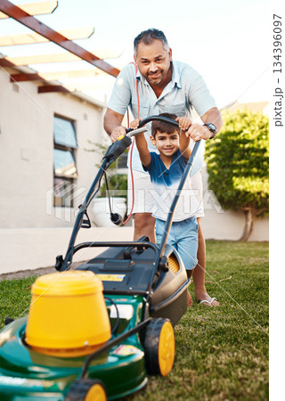 Portrait of happy father, child and lawn mower in garden for helping to cut grass, backyard or learning responsibility. Dad, boy and kid in teaching life skills with gardening machine for outdoor fun 134396097