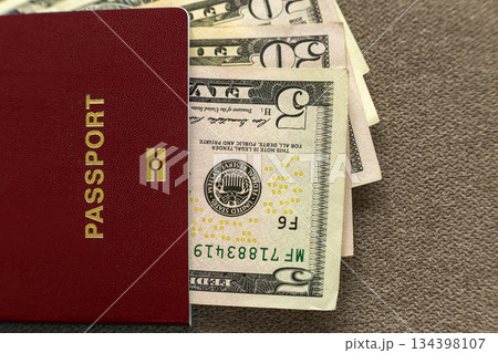 Travel passport and money, American dollars banknotes bills on copy space background, top view. Traveling and finance problems concept. Travel passport and money, American dollars banknotes bills on copy space background, top view. Traveling and finance problems concept. 134398107
