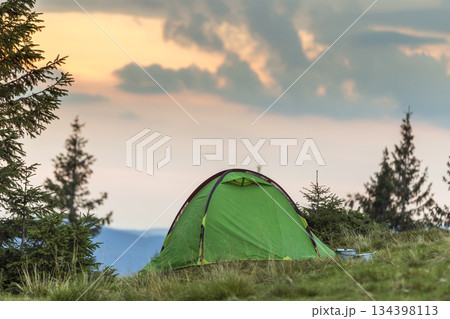 Small tourist tent on grassy mountain hill. Summer camping in mountains at dawn. Tourism concept. Small tourist tent on grassy mountain hill. Summer camping in mountains at dawn. Tourism concept. 134398113
