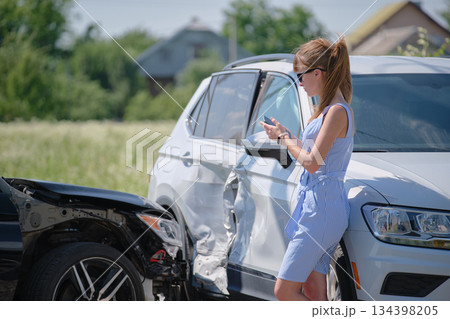 Sad female driver speaking on sellphone on street side calling for emergency service after car accident. Road safety and insurance concept 134398205