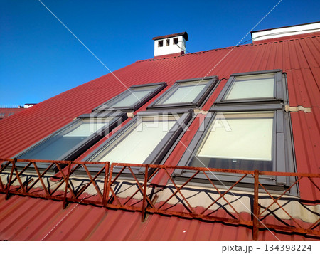 Red tiled house roof with attic windows. Roofing construction, window installation, modern architecture concept. Red tiled house roof with attic windows. Roofing construction, window installation, modern architecture concept. 134398224