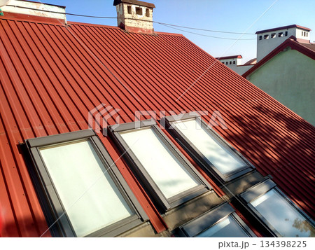 Red tiled house roof with attic windows. Roofing construction, window installation, modern architecture concept. Red tiled house roof with attic windows. Roofing construction, window installation, modern architecture concept. 134398225