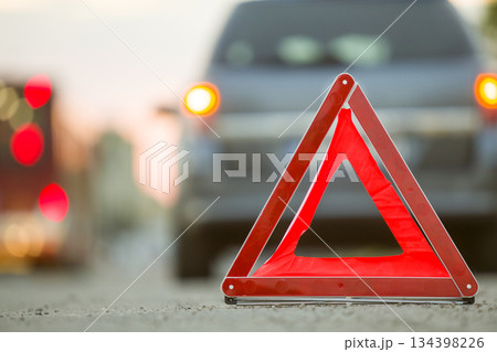 Red emergency triangle stop sign and broken car on a city street. 134398226