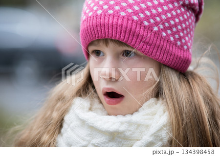 Pretty child girl in warm knitted winter clothes outdoors. 134398458