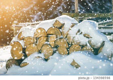 Neatly piled stack of chopped dry trunks wood covered with snow outdoors on bright cold winter sunny day, big snowflakes abstract background, Fire wood logs prepared for winter, ready for burning. Neatly piled stack of chopped dry trunks wood covered with snow outdoors on bright cold winter sunny day, big snowflakes abstract background, Fire wood logs prepared for winter, ready for burning. 134398598