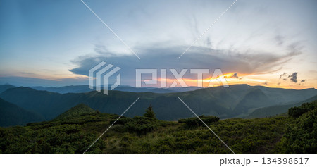 Misty evening over high mountain peaks and distant valley at bright sunset. Amazingl scenery of wild hillside at dusk 134398617