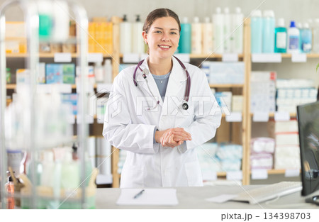 Smiling young female pharmacist inviting for consultation at drugstore Smiling young female pharmacist inviting for consultation at drugstore 134398703