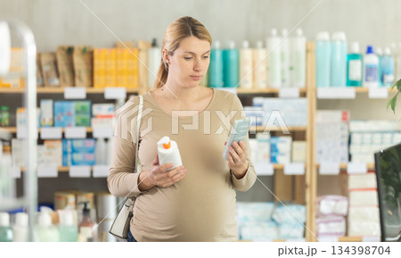 Pregnant woman choosing cream in drugstore Pregnant woman choosing cream in drugstore 134398704
