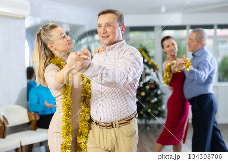 Couples dancing during Christmas - men and women dancing tango or samba next to Christmas tree 134398706