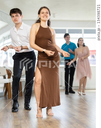 Couple in evening dresses enjoys pair dance boogie-woogie, interacting with each other on floor 134398721