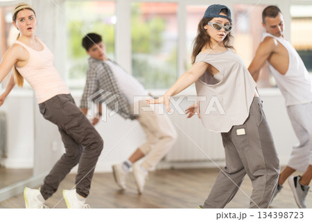 Young girl standing performs basic hip hop movements in front of group of students Young girl standing performs basic hip hop movements in front of group of students 134398723
