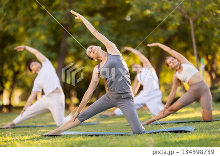 Woman performing yoga asanas during group session in park 134398759